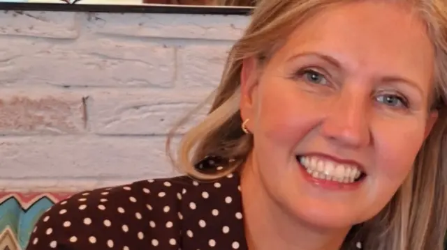 Joanne smiles as she wears a polkadot top