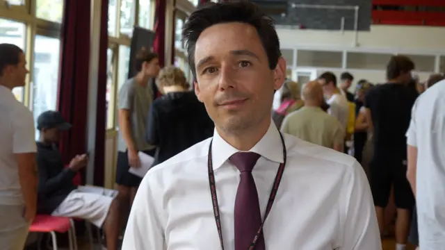 Deputy headteacher at Mayflower High School in Billericay, Luke Kilvert wearing a white shirt and red tie on results day