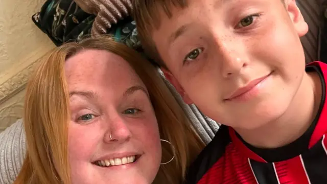 Sian and her son Lucas, she has red hair and he is wearing a black and red football shirt