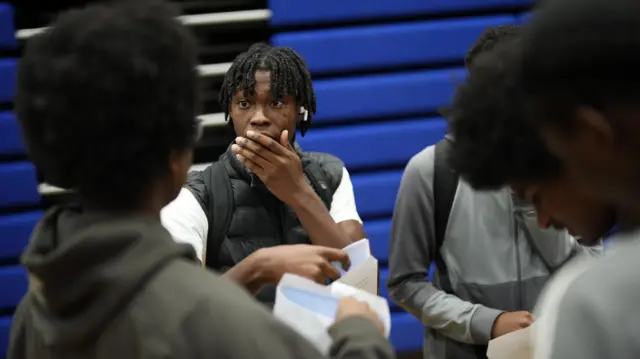 A pupil is in shock as he opens his envelope. He holds his hand to his mouth