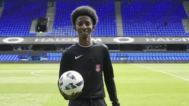 Nasser Hamid holding a football on a football pitch.