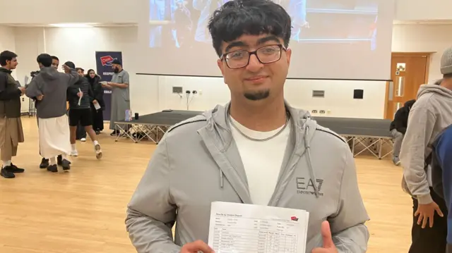 Hisham holding up his results