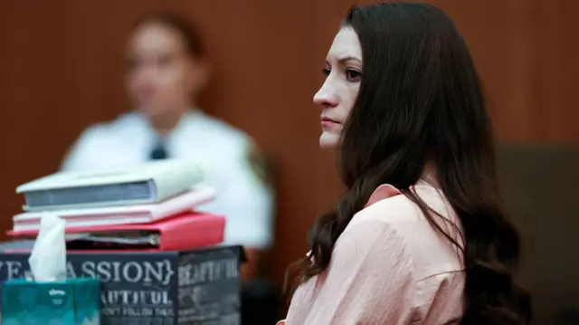 Lindsay Clancy sits in court wearing a light pink shirt