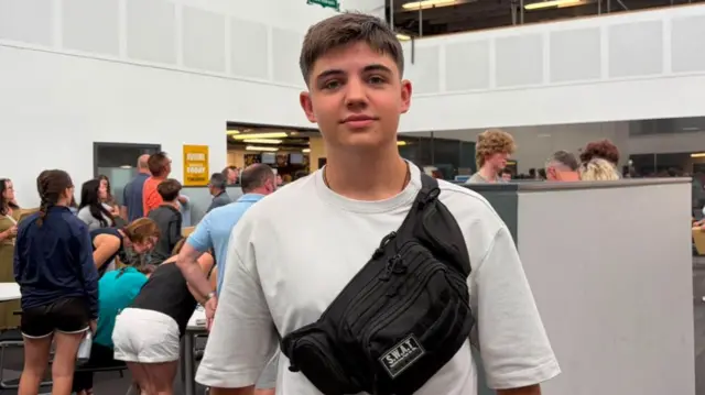 Yaroslav standing in his college wearing a white tshirt and block bag