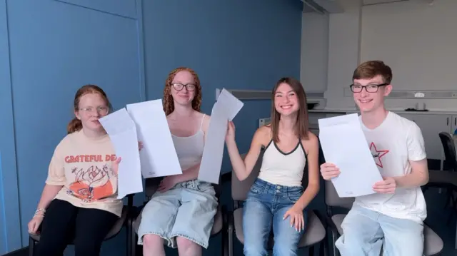 Rose, Ellen, Layla and Eric all hold up pieces of paper with their results on