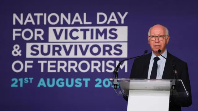 Gerald Oppenheim is pictured speaking from a podium in front of a purple background