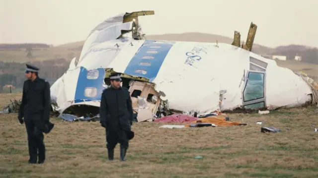 Two policeman walk in front of wreckage of Pan Am Flight 103 after Lockerbie bombing