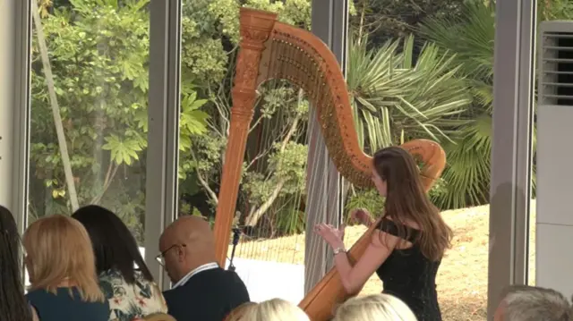 A musician is pictured playing a harp at the ceremony.