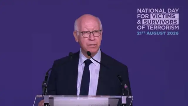 Gerald Oppenheim is pictured speaking from a podium in front of a purple background