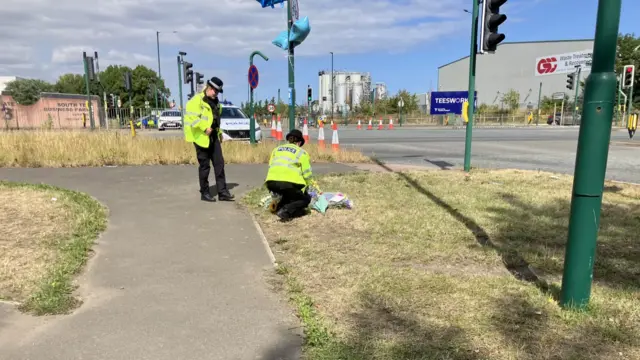 Police officers leaving flowers at scene of crash