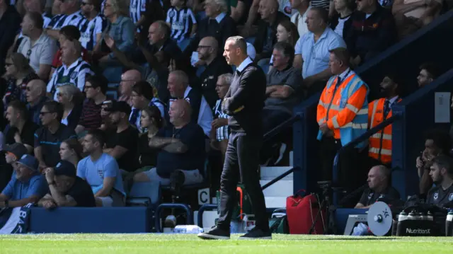 Nicky Hayen stands with his arms folded in the technical area watching the action