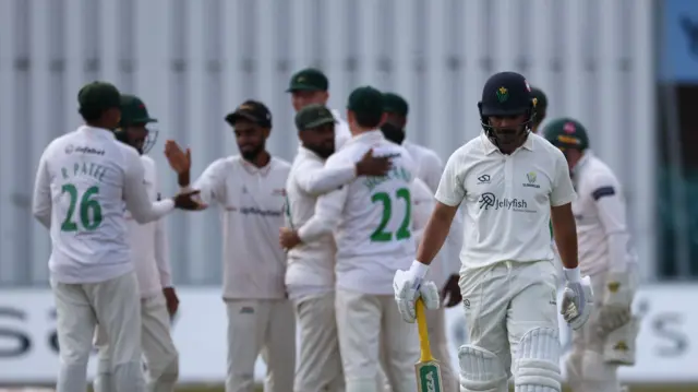Leicestershire players celebrate in the background as a Glamorgan batter leaves the field