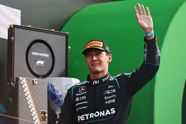 George Russell waves on the podium