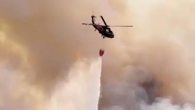A Nevada National Guard helicopter drops water on the Hawk Fire, as the wildfire burns, in Reno