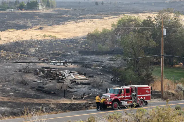 Firefighters pack their truck after responding to a burned building during the Hawk Fire