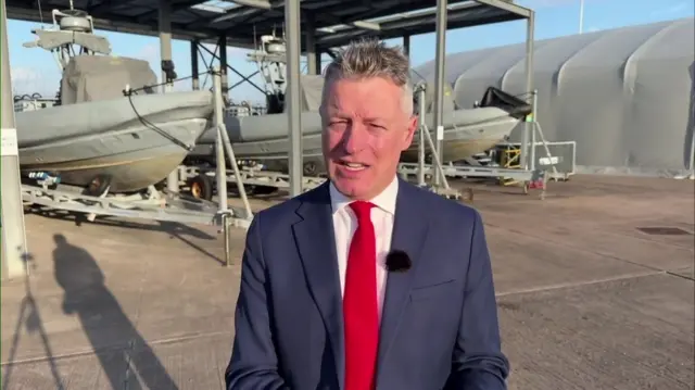 Defence minister Luke Pollard, a man wearing a suit and red tie, standing in an industrial yard.