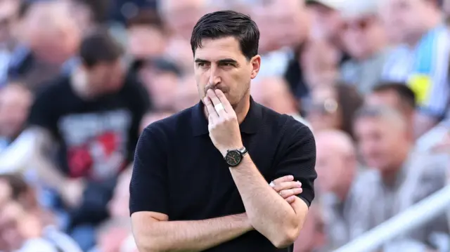 Liverpool head coach Andoni Iraola. He is wearing a black shirt and has his fingers against his mouth.