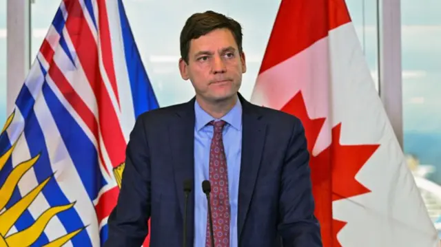 David Eby stands behind a lecturn in a suit