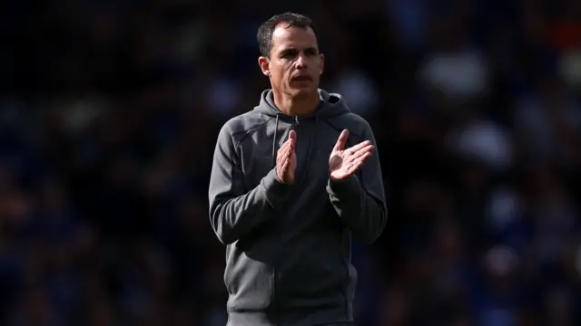 Sunderland head coach Regis le Bris. He is wearing a grey jumper and is applauding to the Sunderland fans.