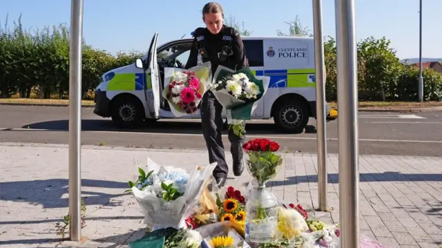 A police officer leaves flowers at the Cleveland Police HQ Memorial Garden in Middlesbrough