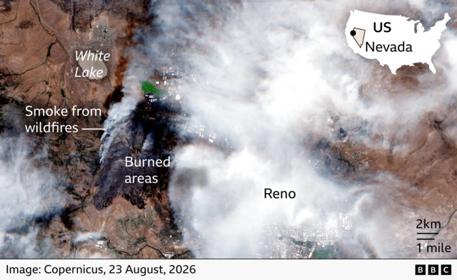 Satellite image showing smoke and burned land from wildfires west of Reno, Nevada. Cloud covers much of the area around the city, but smoke from fires are visible near the charred ground near White Lake. An inset map locates the scene within Nevada in the western United States.