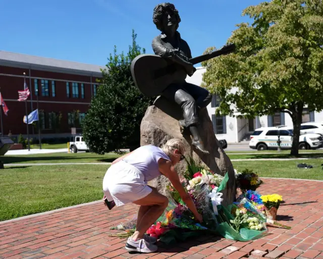 A woman leaves flowers at a statue of Dolly Parton in downtown Sevierville, Tennessee