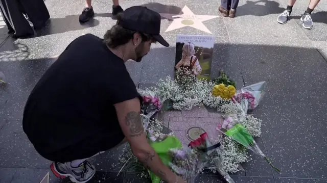 Man placing flowers on Dolly Parton's star on the Hollywood Walk of Fame