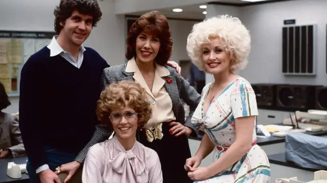 actresses posing with director in office