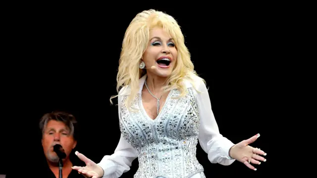 Dolly Parton at Glastonbury, wearing a white rhinestone suit