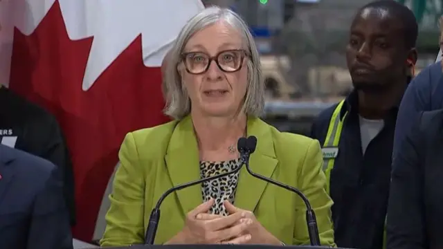 Patty Hadju wearing a bright green blazer and speaking into a podium