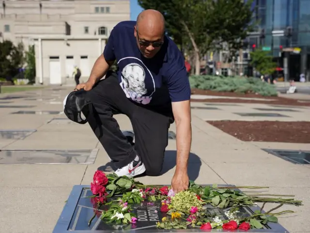 David Ewing, wearing a Dolly Parton shirt, places flowers at the star of Dolly Parton at the Music City Walk of Fame