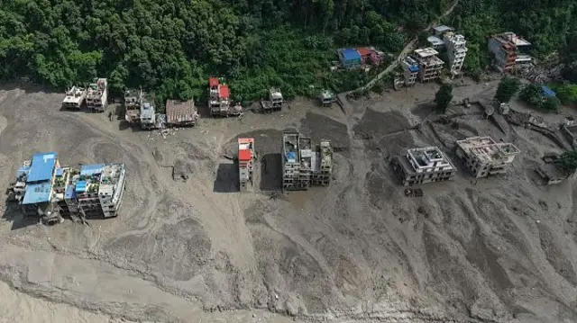 Residental housing blocks covered in mud and partially submerged are visible from a birds eye view