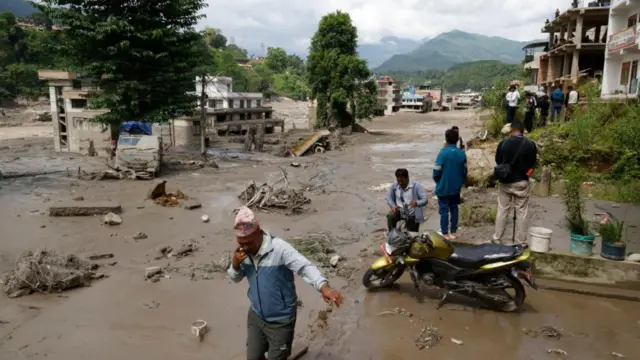 Villagers wade through flooded streets