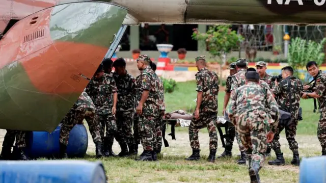 Military troops are shown loading a person on a stretcher onto an aircraft