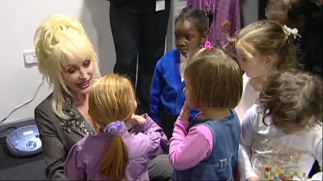 Dolly kneeling down to speak to young girls