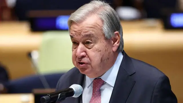 Guterres speaking into a microphone at an event.