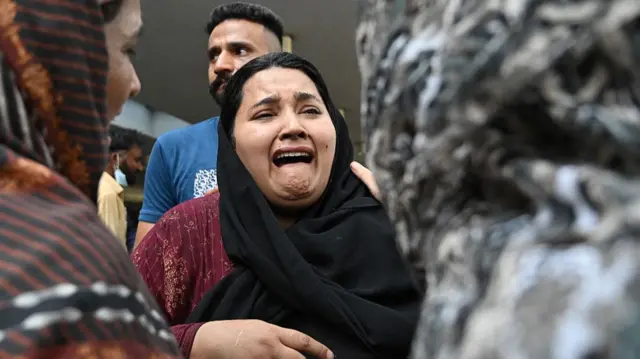 A crying woman outside PIMS hospital in Islamabad, Pakistan where a fire killed 14 newborns