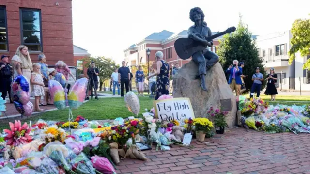 Floral tributes line up next to a statue of Dolly Parton playing a guitar in Tennessee