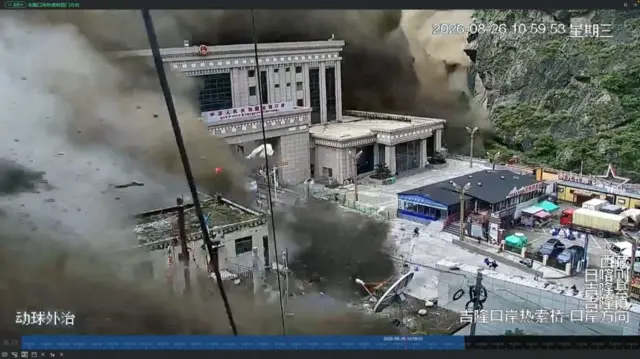 An enormous wall of muddy water is shown slamming into buildings that are at least six storeys high.