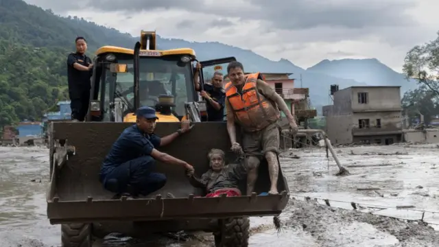Rescuers transport an elderly woman in Trishuli Bazar, Nuwakot district, Nepal