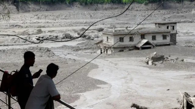 People watch floodwaters sweeping through Trishuli Bazar following a flash flood in Nepal