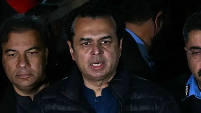 Talal Chaudhry is pictured speaking at a press conference at night-time.