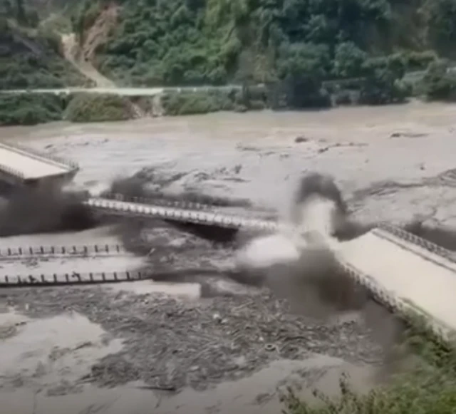 Screenshot of a video showing debris from a bridge smashing another bridge in two