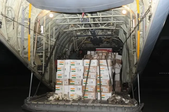 aid boxes marked with the indian flag are seen filling the body of an aircraft.