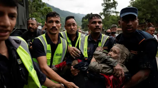 Police officers carry a survivor to a safer place following a flash flood at Trishuli in Nuwakot district