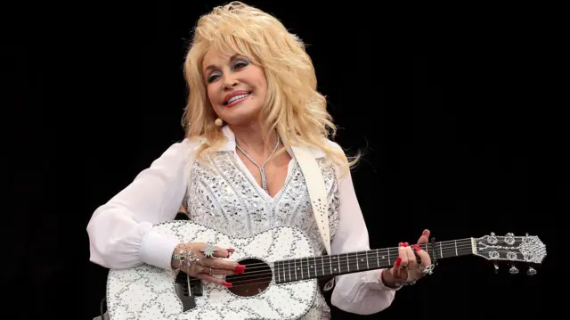 Dolly Parton performs with a guitar in hand
