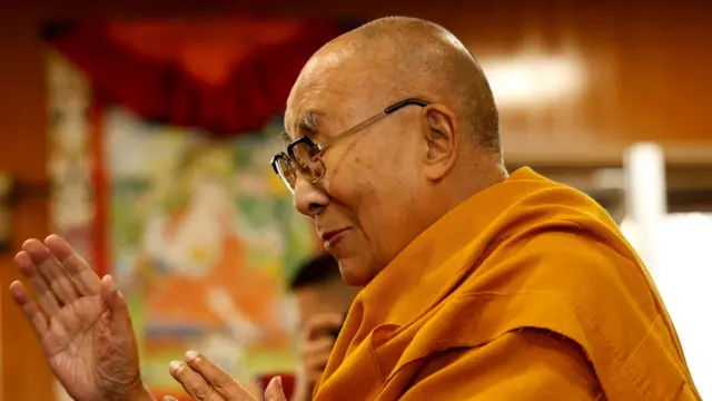 A side view of the Dalai Lama as he offers a blessing