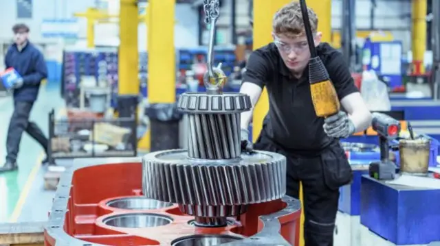 A young man in a factory using a machine.
