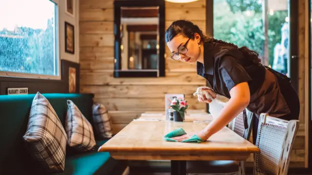 A young cafe worker wiping down a table.