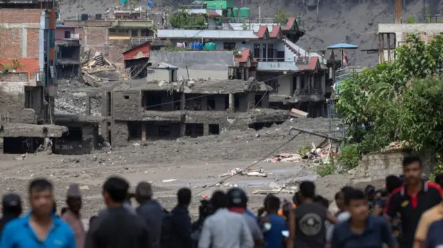 People watch as floodwaters sweep through Trishuli Bazar following a flash flood, in Nuwakot district, Nepal